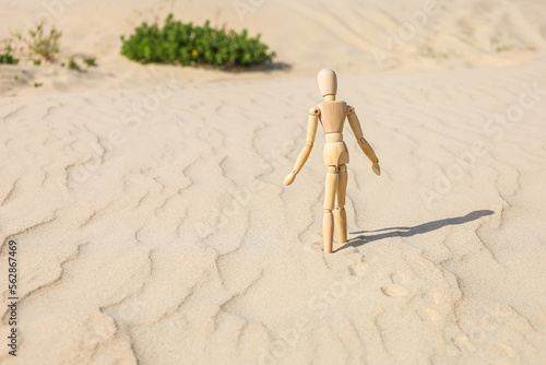 Wooden mannequin on sand, back view