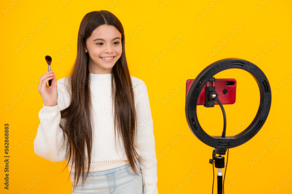 Teenager recording online media video. Teen girl streaming online and sharing social media content by mobile phone app network, isolated on yellow studio background. Beauty blog. Teenager recording online media video. Teen girl streaming online and sharing social media content by mobile phone app network, isolated on yellow studio background. Beauty blog.