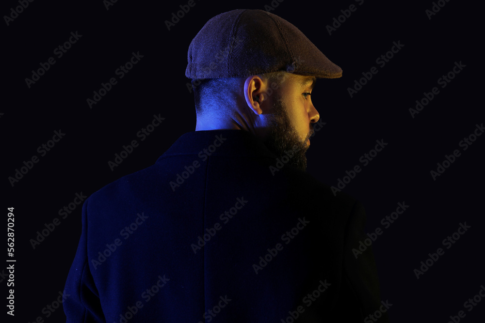 Silhouette of young man in cap on dark background, back view Silhouette of young man in cap on dark background, back view