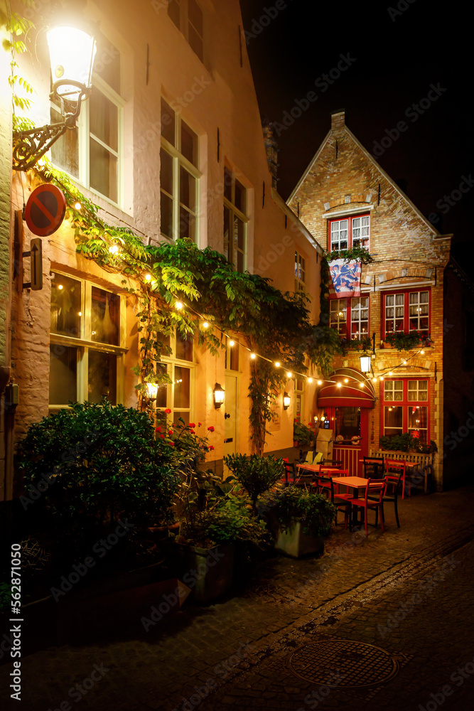 Cozy restaurant on the streets of the old town at night. Paving stones of night Brugge.