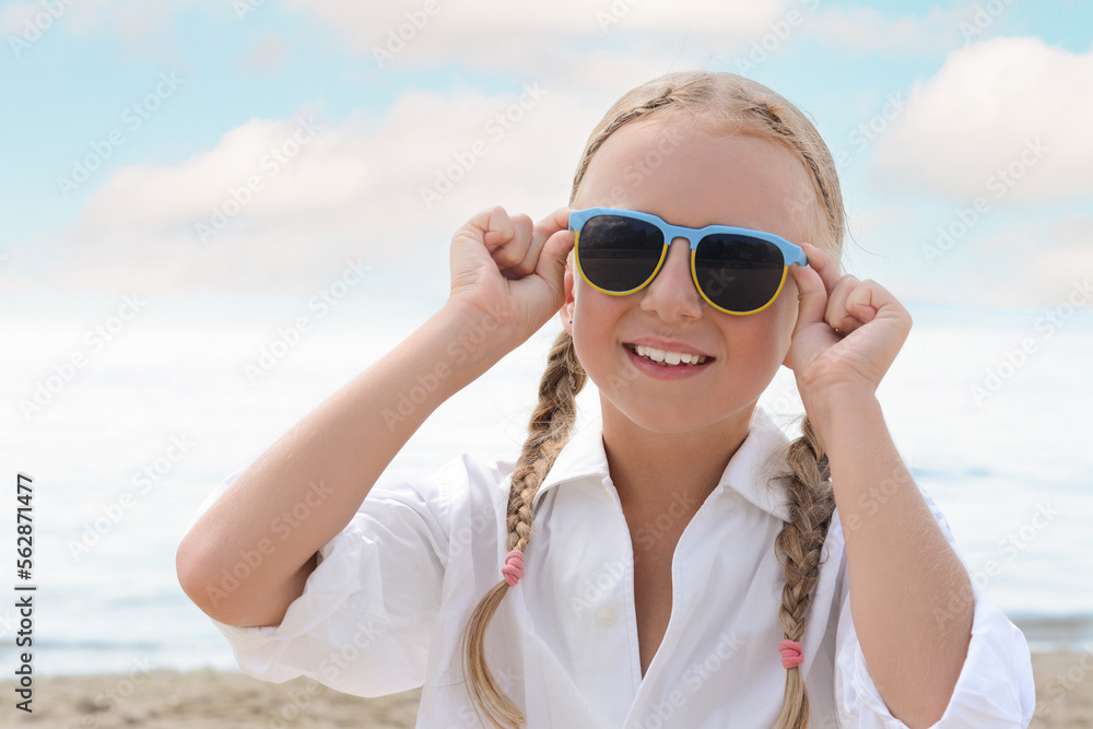 Little girl wearing sunglasses at beach on sunny day Little girl wearing sunglasses at beach on sunny day