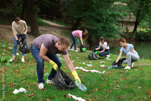 Group of people with plastic bags collecting garbage in park photo