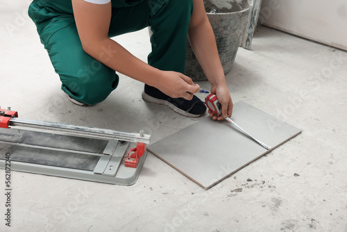 Worker measuring ceramic tile on floor, closeup