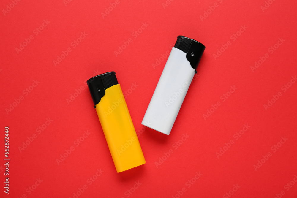 Stylish small pocket lighters on red background, flat lay Stylish small pocket lighters on red background, flat lay