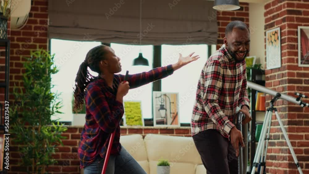 Funny people showing dance moves and tidying up apartment, mopping and