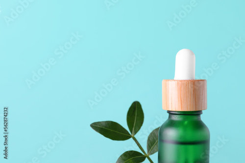 Bottle of serum and plant leaf on color background