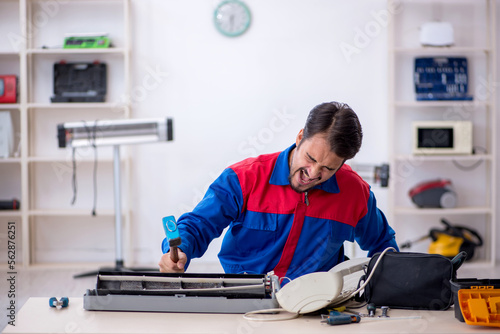 Young male repairman repairing air-conditioner