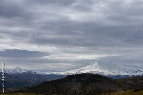 Fototapeta Naklejka Na Ścianę i Meble -  Big mountain Elbrus against the blue sky. View from a large plateau and steep cliffs.