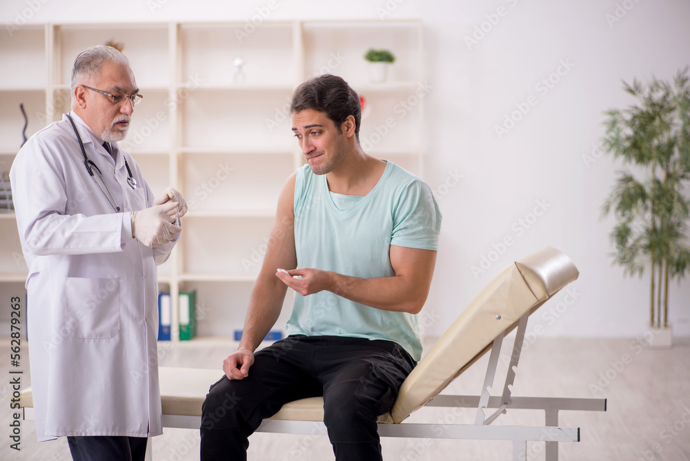 Fototapeta premium Young male patient visiting old male doctor in vaccination conce