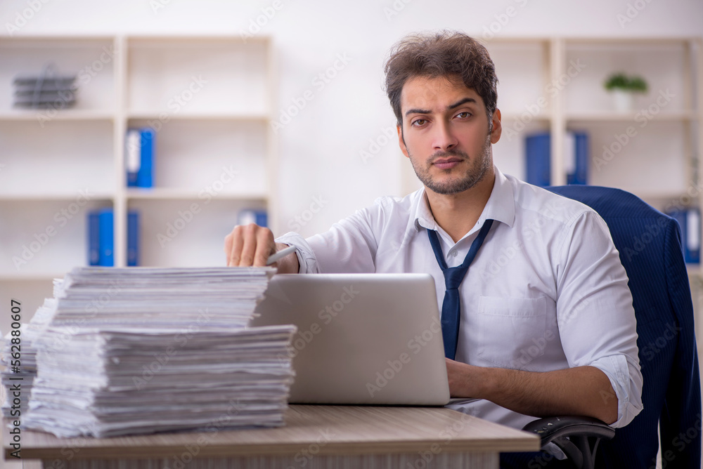 Young male employee and too much work in the office Young male employee and too much work in the office