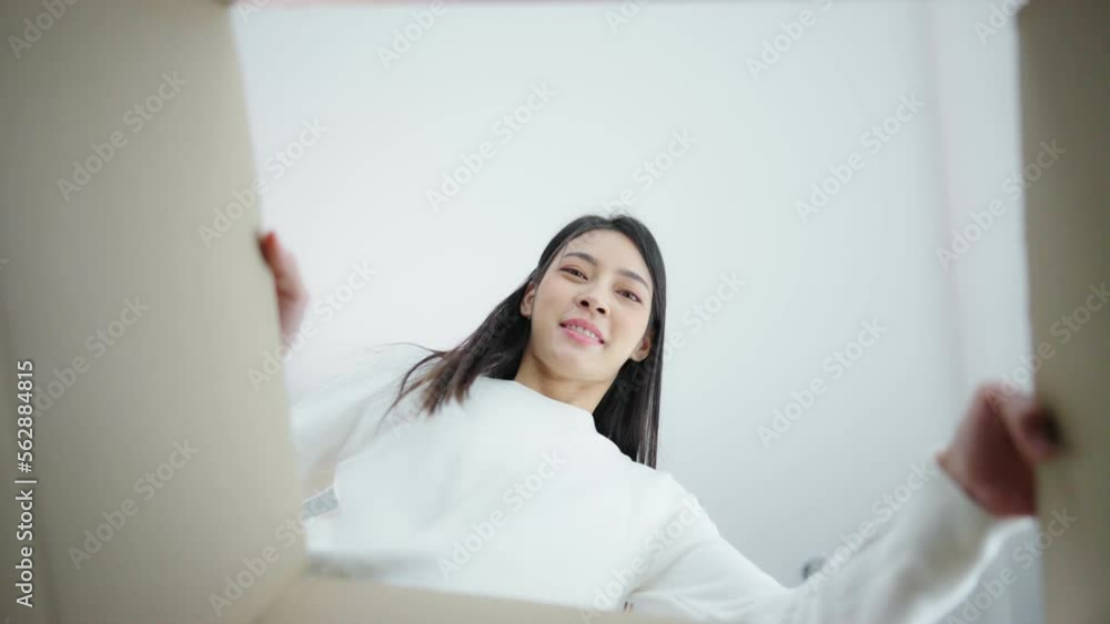 Surprised young asian woman unpacking. Opening carton box and looking inside. Packaging box, delivery service. Human emotions and facial expression Surprised young asian woman unpacking. Opening carton box and looking inside. Packaging box, delivery service. Human emotions and facial expression