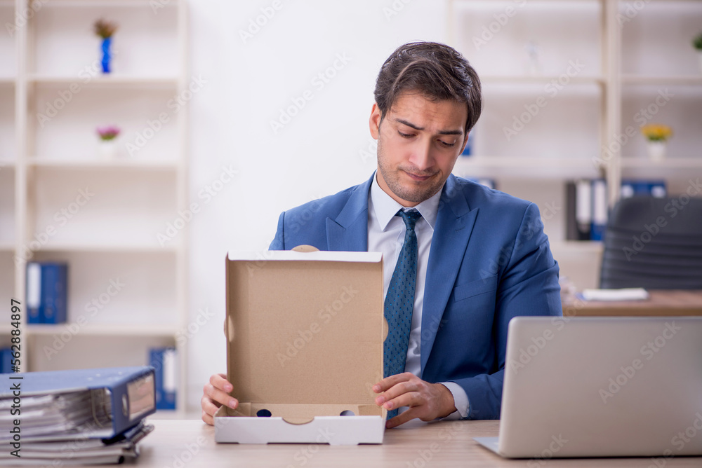Young male employee eating pizza at workplace Young male employee eating pizza at workplace