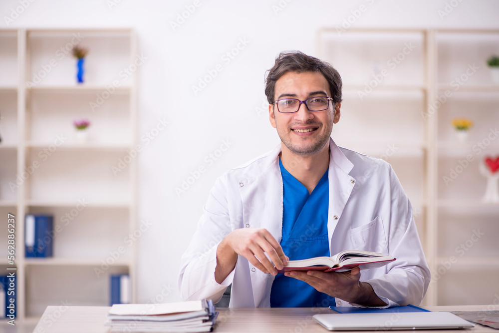 Young male doctor student reading book in the clinic Young male doctor student reading book in the clinic