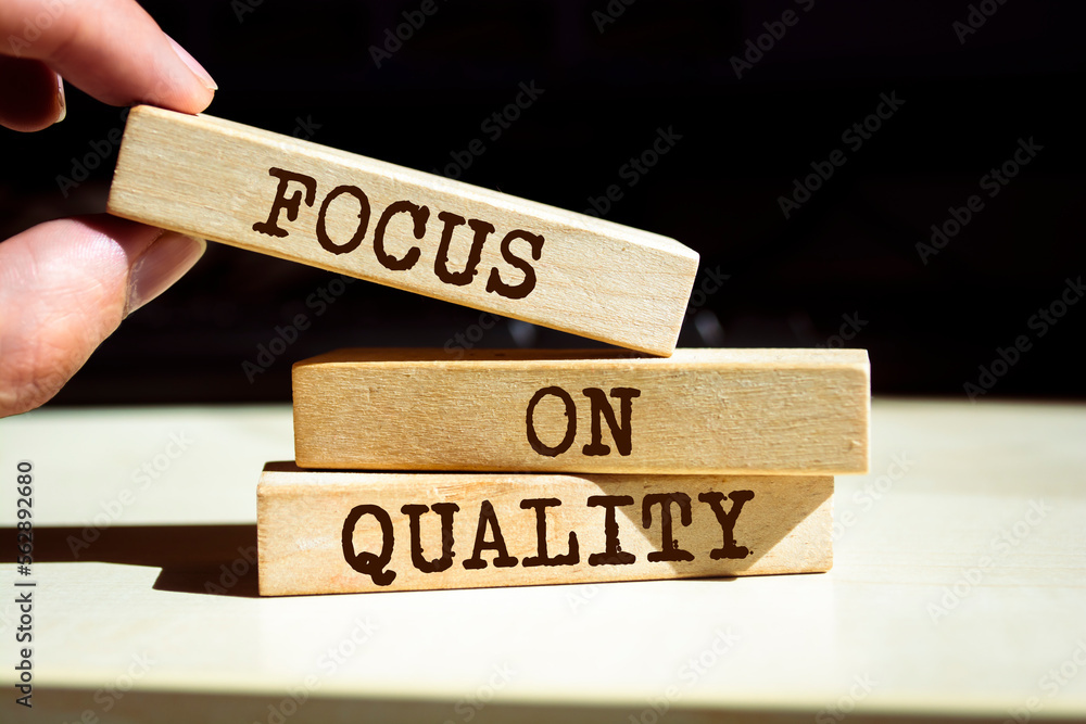 Closeup on businessman holding a wooden blocks with text 'FOCUS ON QUALITY', business concept Closeup on businessman holding a wooden blocks with text 'FOCUS ON QUALITY', business concept