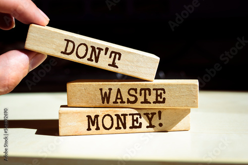 Closeup on businessman holding a wooden blocks with text 'Don't waste money', business concept