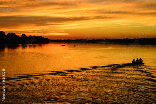 The silhouette of a small motorized canoe against a golden sunset on the Guaporé - Itenez river, Ricardo Franco village, Vale do Guaporé Indigenous Land, Rondonia, Brazil, on the border with Bolivia
