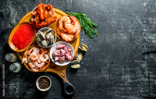 Various seafood on a round cutting Board with herbs and spices.