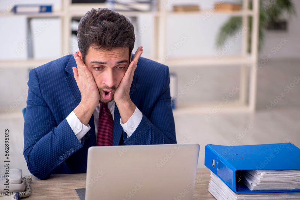 Young male employee and too much work in the office Young male employee and too much work in the office