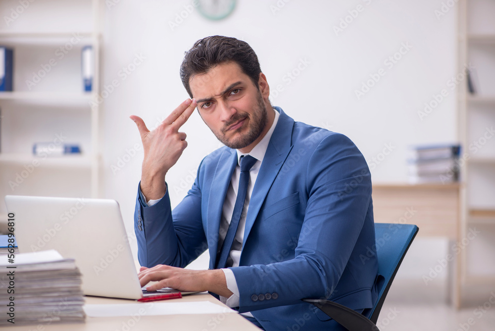 Young male employee and too much work in the office Young male employee and too much work in the office
