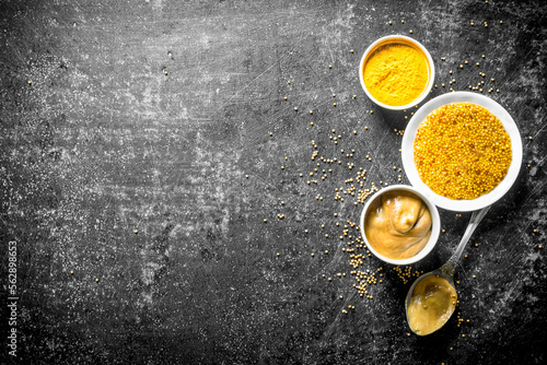 Different types of mustard with a spoon.