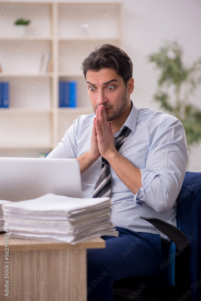 Young male employee and too much work in the office Young male employee and too much work in the office