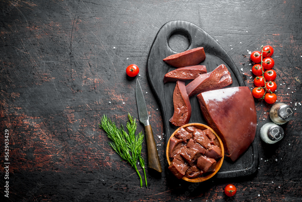 Naklejka premium Raw liver with cherry tomatoes, spices and dill on a cutting Board.
