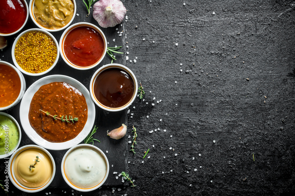 An assortment of different sauces in bowls on a stone Board. An assortment of different sauces in bowls on a stone Board.