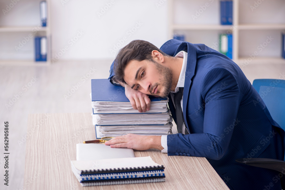 Young male employee and too much work in the office Young male employee and too much work in the office