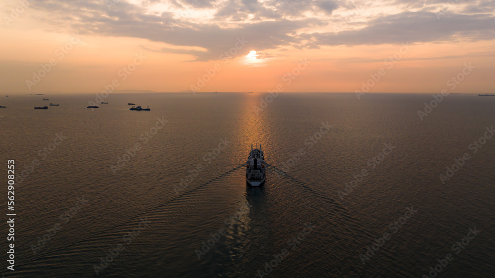 Seascape and silhouette container ship floating in sea and over the sunlight background,