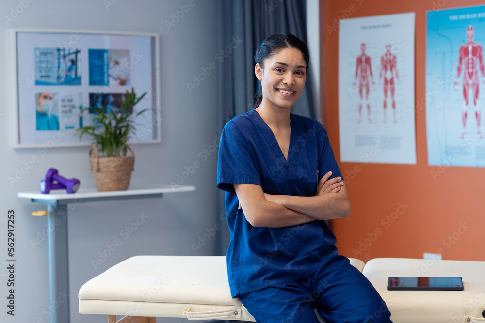 Portrait of biracial female physiotherapist smiling in hospital therapy room, copy space - obrazy, fototapety, plakaty 