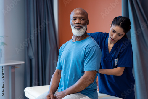 Quadro em tela Diverse female physiotherapist treating back of senior male patient in hospital,