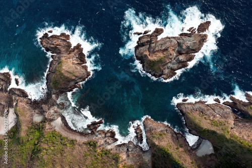 Obraz na płótnie View from above, stunning aerial view of a rocky coastline with some ocean waves crushing on the shore. Lombok Island, West Nusa Tenggara, Indonesia. w salonie