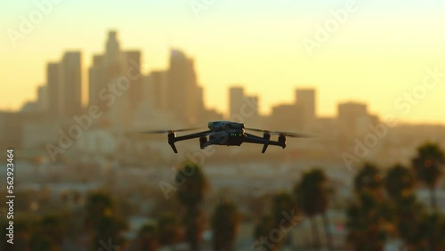 4k footage Drone flies along the skyline against the backdrop of a golden sunset in downtown Los Angeles. Black quadrocopter flies against the palm trees and skyscrapers. California, USA