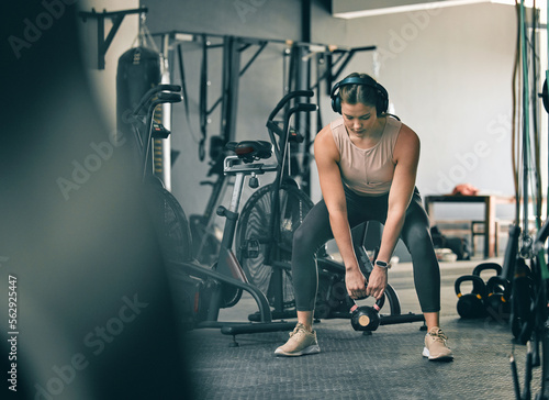 Kettlebell weight, fitness gym woman with workout, training and exercise with headphones. Sport focus, wellness and healthy athlete busy with muscle and cardio development in a health studio