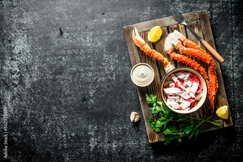 Crab meat and fresh crab on a wooden tray with lemon slices, sauce and herbs. © Artem Shadrin