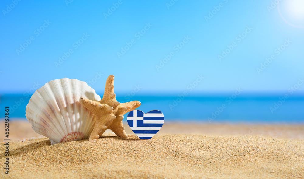 Beautiful beach in Greece. Flag of Greece in the shape of a heart and shells on a sandy beach.
