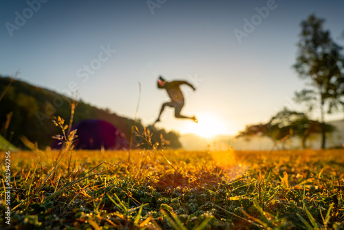 silhouette of a jumping person in a field at sunrise