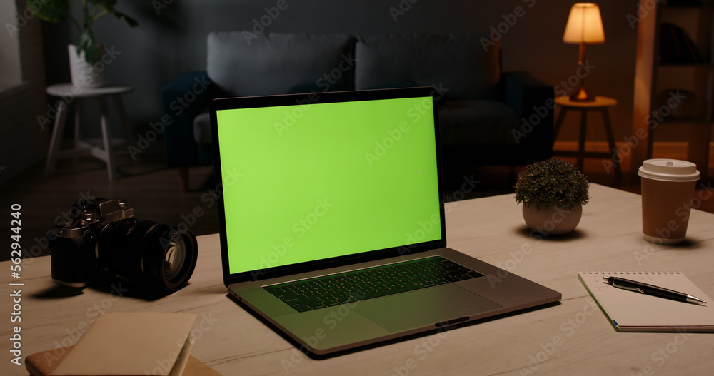 Fototapeta premium Close up shot of modern chroma key green screen laptop computer set up for work on desk at night - remote work, technology concept 
