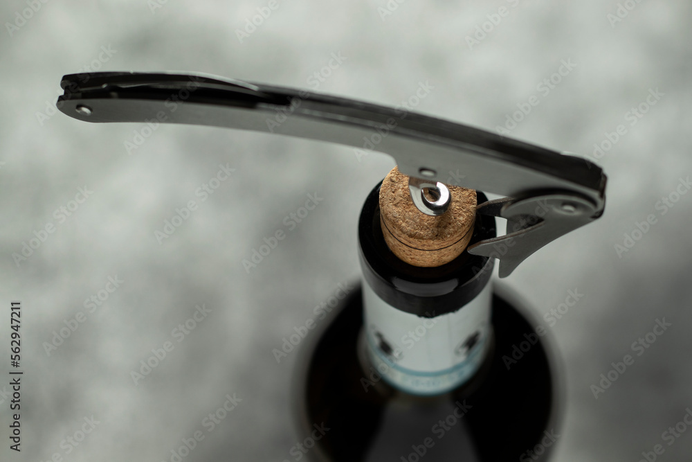 Obraz premium Bottle, corkscrew and cork on a black background. Selective focus.