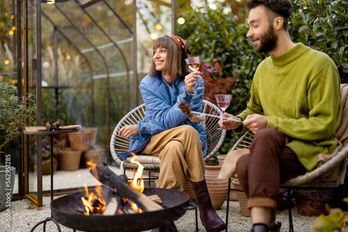 Photography Young stylish couple grilling food and warming up while sitting together by the