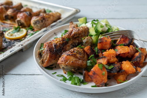 Chicken drumsticks with roasted sweet potatoes and cucumber salad on a plate