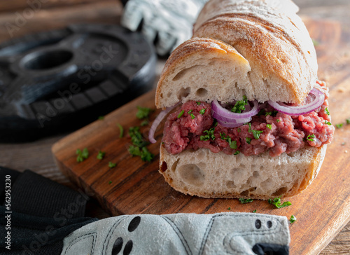 Tableau sur toile Muscle building Tatar or raw beef cannibal sandwich with parsley and red onions on wooden table