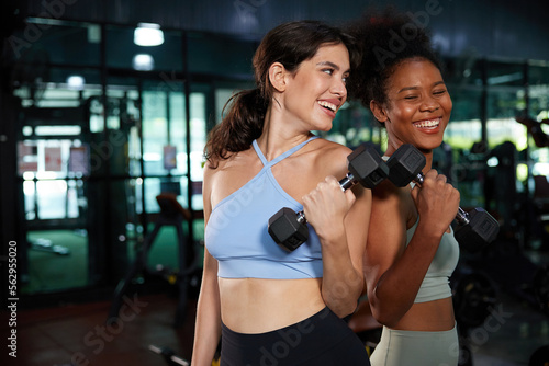 young athletic women smiling and lifting dumbbell in the gym