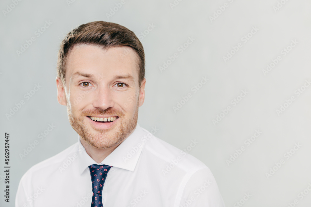 Studio shot of handsome unshaven male entrepreneur with cheerful expression, rejoices raising sales, dressed in formal clothes, isolated over white background with copy space aside for your text Studio shot of handsome unshaven male entrepreneur with cheerful expression, rejoices raising sales, dressed in formal clothes, isolated over white background with copy space aside for your text