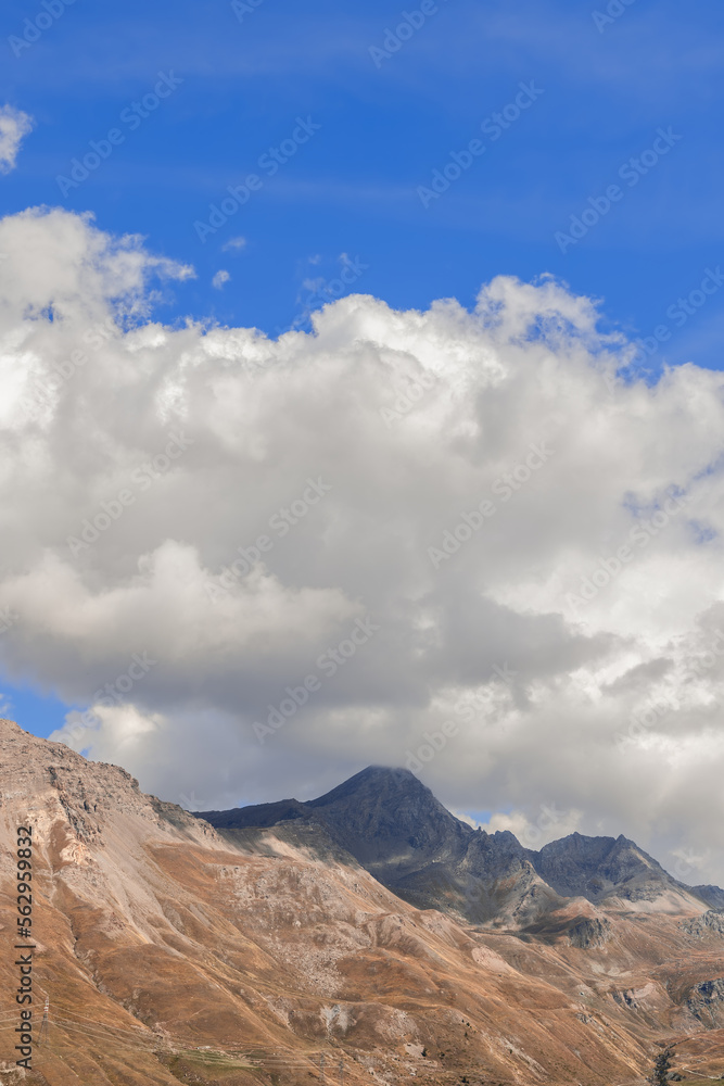 Tricolour (blue, white, yellow) autumn landscape of mountains, sky and clouds in the Aosta valley. Italy. Vertical shot