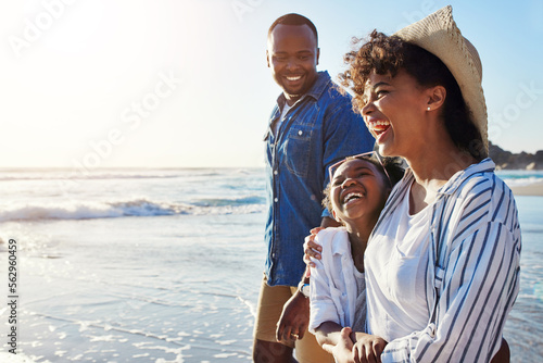 Family, travel and walking on a beach with adorable child on vacation or holiday at the ocean or sea. Summer, mother and father with black kid or daughter holding hands together near water