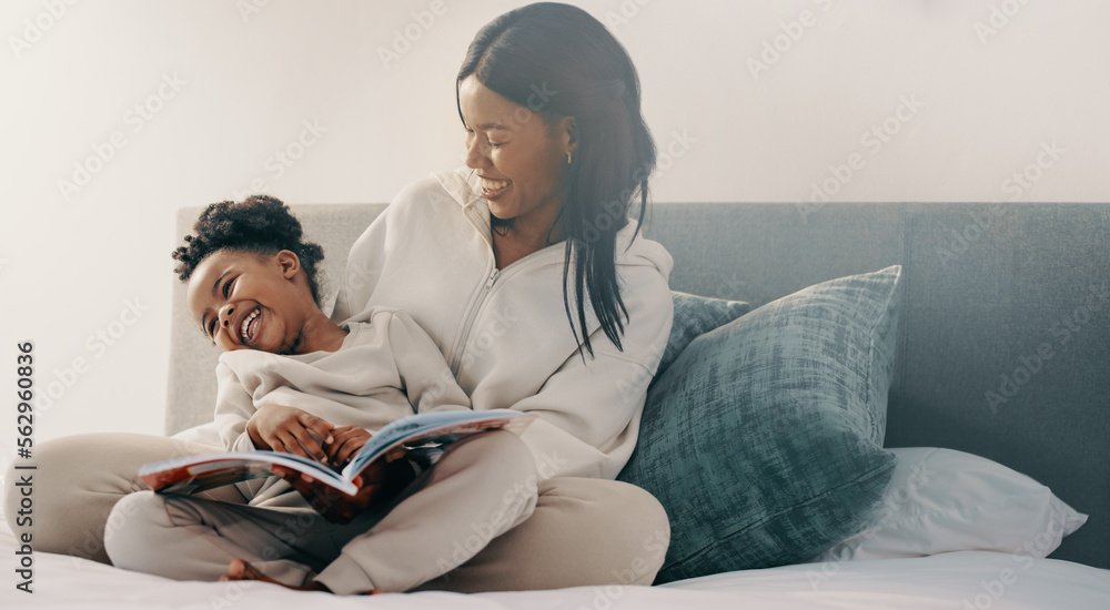 Preschool age girl laughs happily while sitting with her mom reading a story book - obrazy, fototapety, plakaty 