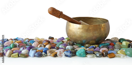 Tibetan singing bowl with mallet, resting on top of a selection of multicoloured tumbled healing stones transparent png file