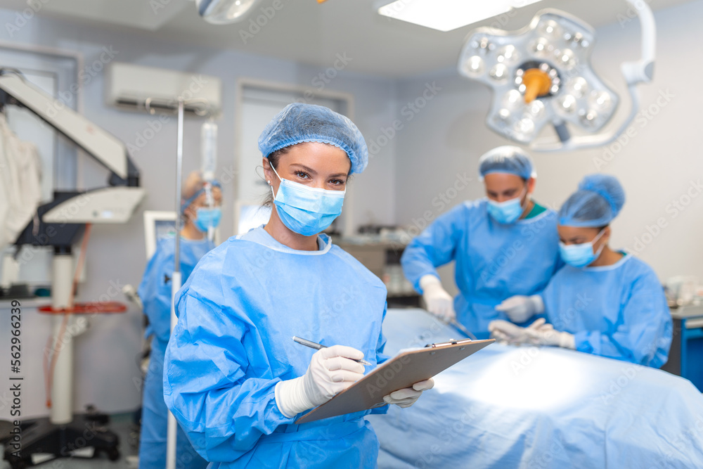Surgeon writing on clipboard in operation room, anaesthesiologist writing the updates Surgeon writing on clipboard in operation room, anaesthesiologist writing the updates