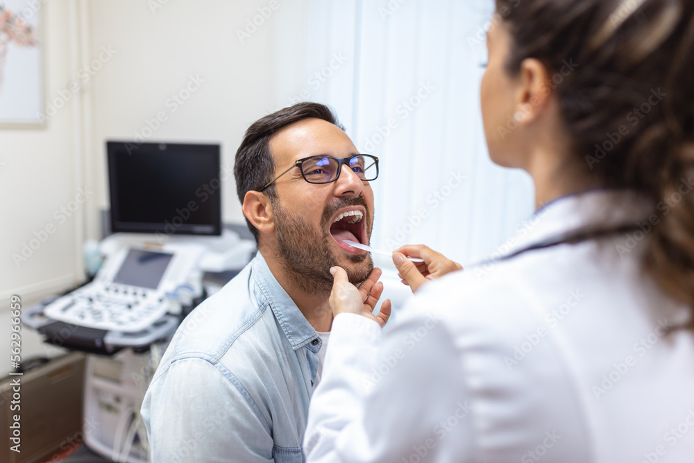 A young man sits on an exam table across from his doctor. The doctor
